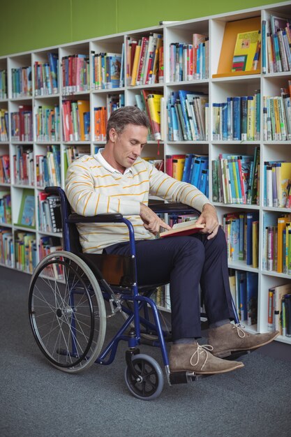 Enseignant d'école handicapé attentif livre de lecture dans la bibliothèque