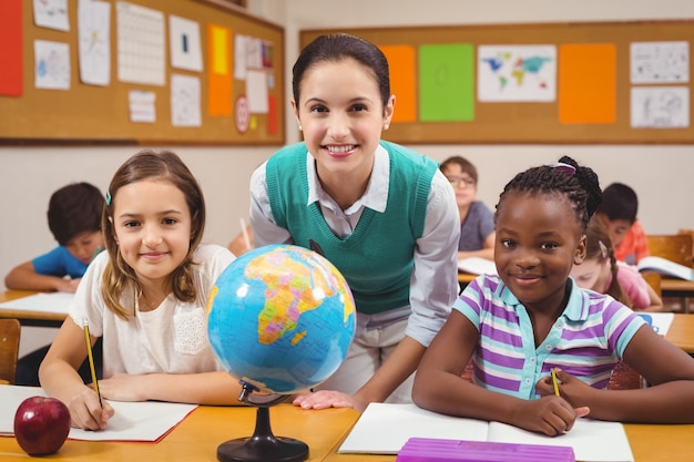 Enseignant et élèves souriant à la caméra dans la salle de classe