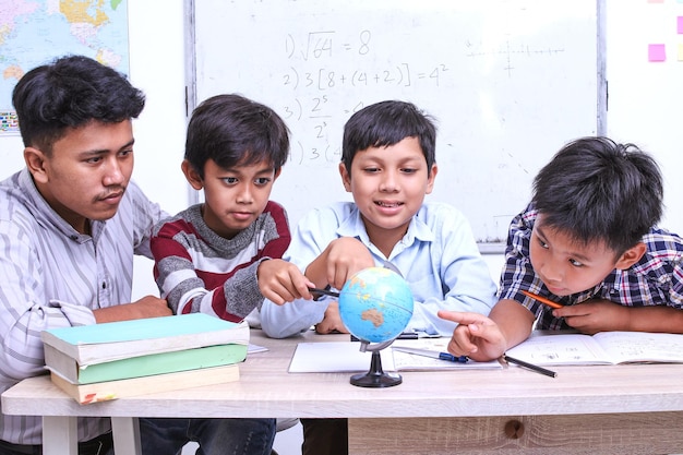 Enseignant et enfants discutant du globe dans la salle de classe