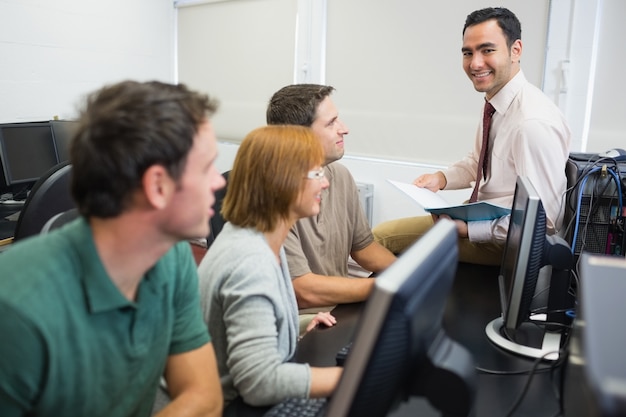 Enseignant et étudiants adultes dans la salle informatique