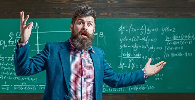 L'enseignant explique les mathématiques au tableau noir, l'enseignant en classe avec le tableau noir, le professeur d'école écrit des mathématiques.