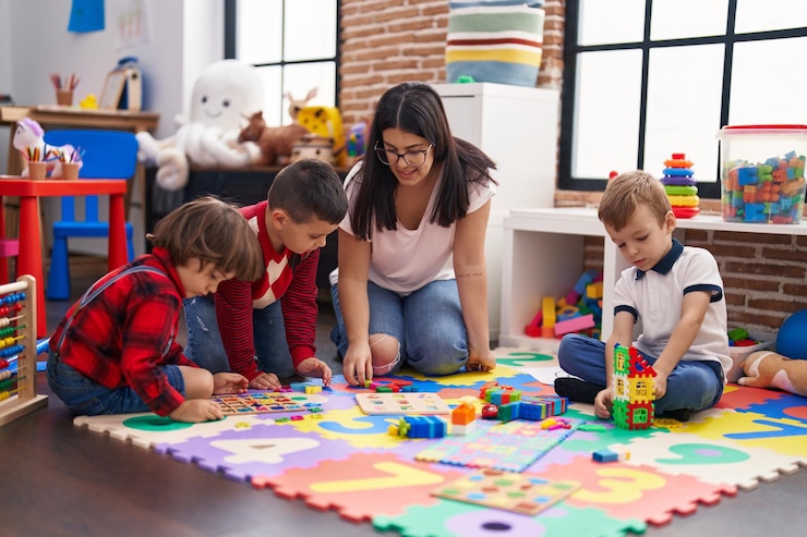 Photo un enseignant avec un groupe de garçons jouant à un jeu de puzzle de mathématiques assis sur le sol à la maternelle