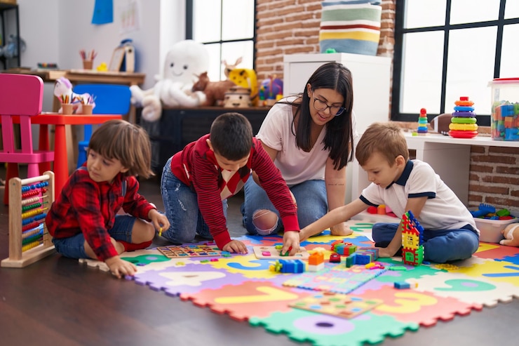 Photo un enseignant avec un groupe de garçons jouant à un jeu de puzzle de mathématiques assis sur le sol à la maternelle