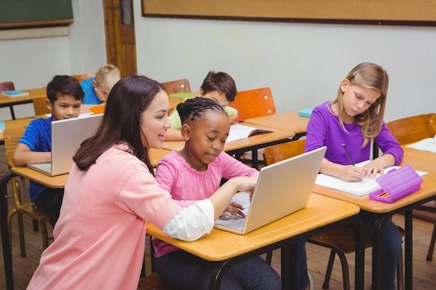 Enseignant heureux en utilisant un ordinateur portable avec un étudiant