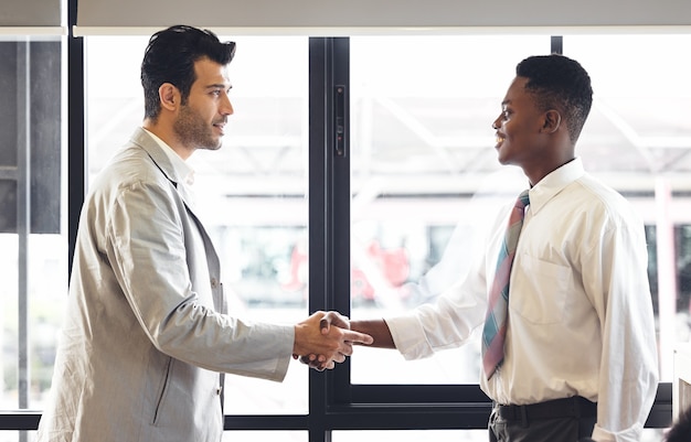 L'enseignant de l'homme se tient debout et serre la main avec des étudiants noirs après avoir réussi. Diversité de deux personnes