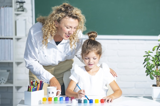 Enseignant avec un jeune écolier en classe. Mère et fille apprenant.