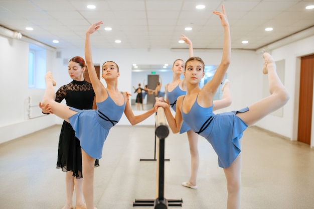 Photo enseignant et jeunes ballerines exercent à la barre en classe