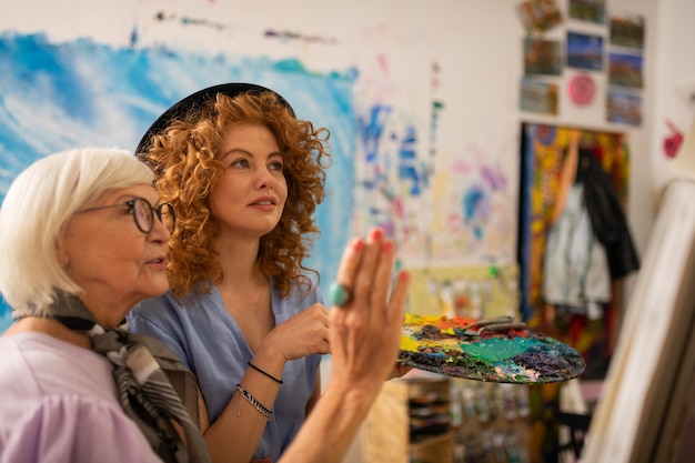 Photo enseignant à lunettes. professeur d'art à lunettes satisfait du travail de sa jeune élève aux cheveux roux