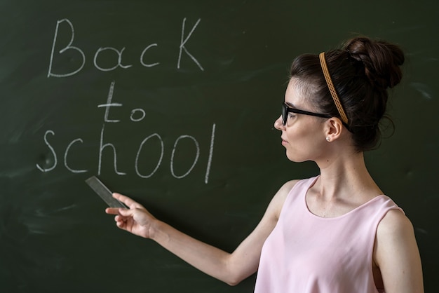 Enseignant près du tableau noir, écrit de nouveau à l'école, concept d'éducation