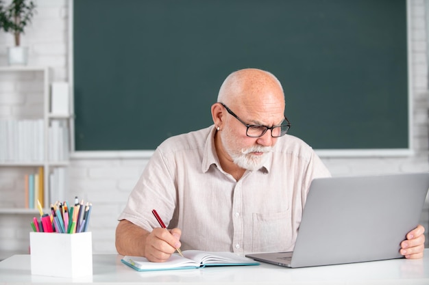 Enseignant principal en classe à l'université ou au collège Ancien étudiant de sexe masculin à bord avec un ordinateur portable