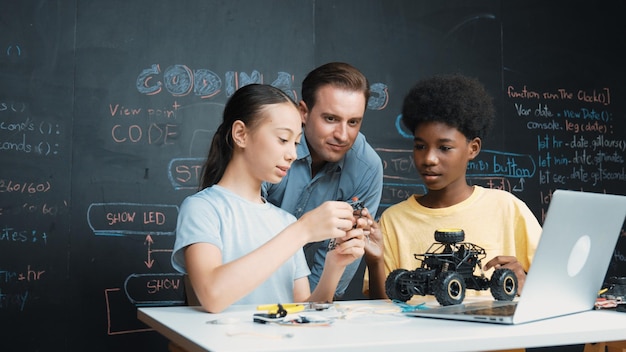 L'enseignant regarde l'écran de l'ordinateur portable tout en expliquant le système de modèle de voiture Edification