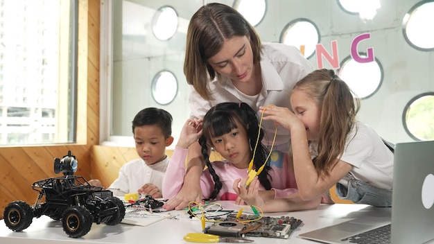 Photo l'enseignant regarde les enfants tandis que l'élève diversifié regarde l'écran.