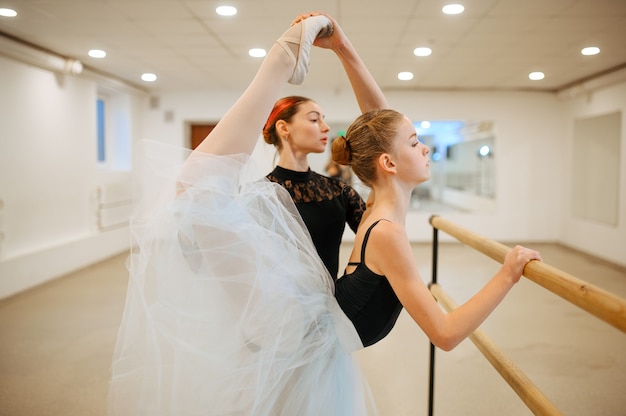 Enseignant en répétition avec une jeune ballerine à la barre en classe