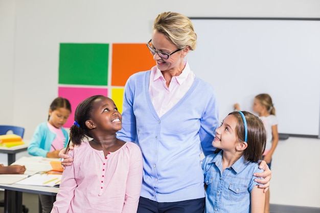 Enseignant souriant et enfants debout avec le bras autour