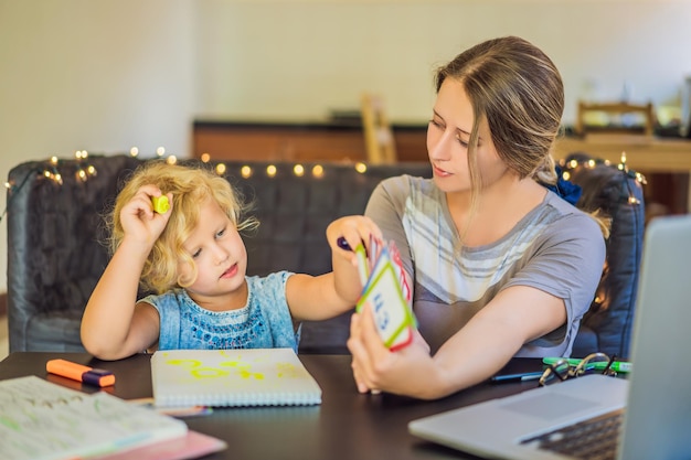 Un enseignant un tuteur pour l'enseignement à domicile et un enseignant à table Ou maman et sa fille L'enseignement à domicile