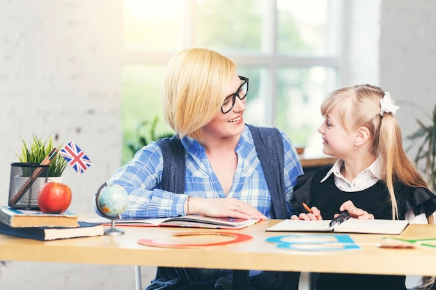 Enseignante d'anglais étudiant avec une fille intelligente dans une salle de classe blanche claire concept d'apprentissage des enfants