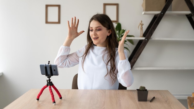 Photo une enseignante donne une leçon vidéo en ligne en zoom sur la caméra du smartphone jeune fille souriante agitant ses mains devant la caméra web du téléphone donnant des conseils webinaire ou formation à distance