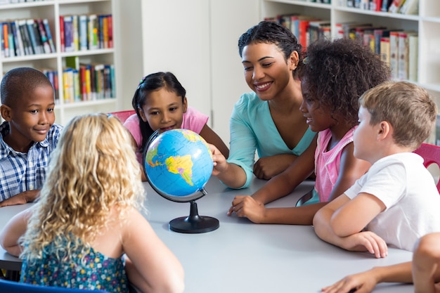 Enseignante enseignant aux enfants à l'aide du globe