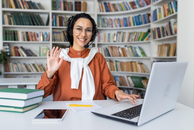 Photo une enseignante heureuse avec un casque est assise devant un ordinateur portable en classe et donne des cours en ligne en souriant.