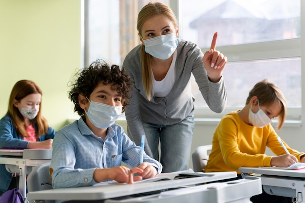 Photo enseignante avec masque médical expliquant la leçon aux étudiants