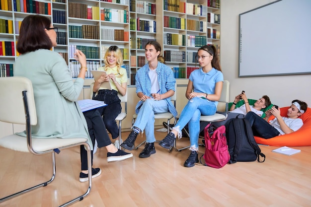 Enseignante mentor travaillant avec des lycéens adolescents de sexe masculin à la bibliothèque