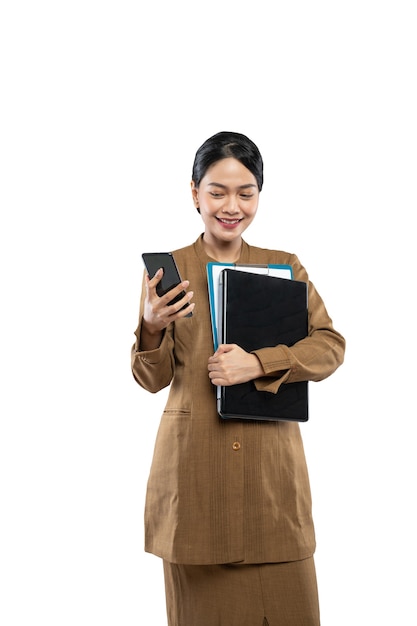 Une enseignante en uniforme passe un appel à l'aide d'un téléphone tout en portant un ordinateur portable