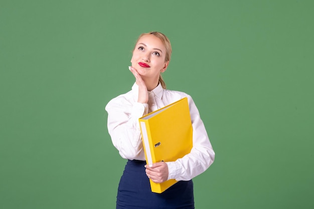 Enseignante vue de face dans des vêtements stricts avec des fichiers jaunes sur vert