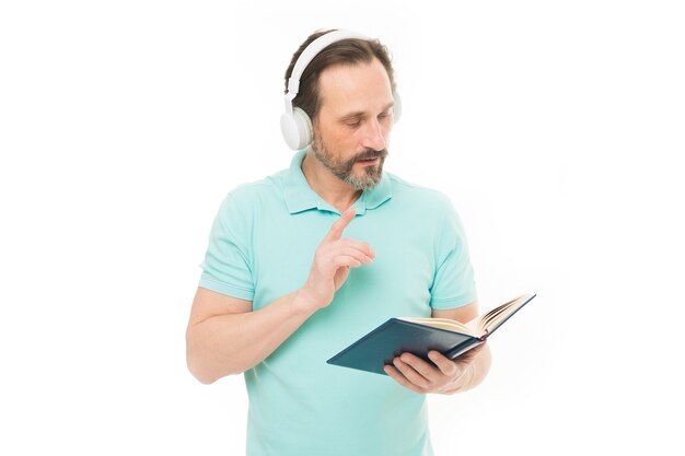 Enseignement et apprentissage à distance. Homme d'affaires âgé apprenant un cours de commerce en ligne. Coach d'affaires senior en casque avec livre. Étudiant mûr écoutant l'ebook. Homme barbu à l'école web.