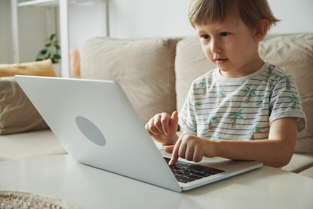 Enseignement à distance de l'enseignement à domicile Enfant utilisant un ordinateur portable assis sur un canapé à la maison