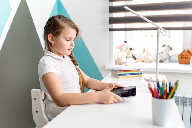 Enseignement à distance en ligne Écolière étudiant à la maison