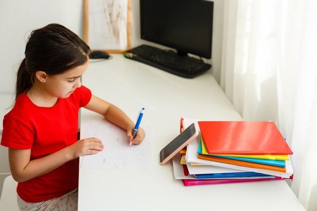 Enseignement à distance en ligne, petite fille écrit des formules