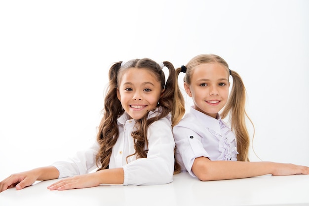 Enseignement à domicile Adorables élèves assis à des bureaux isolés sur blanc Les petits enfants bénéficient de l'enseignement privé Les petites écolières ayant une scolarité obligatoire Années de scolarité