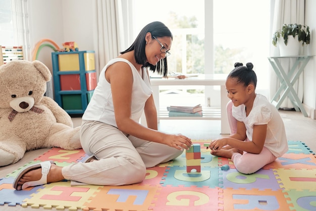 Enseigner le jeu de construction de jouets et la mère avec une fille dans la chambre d'enfant pour la connaissance de la croissance et la résolution de problèmes Maman enfant ou personnes noires ensemble sur un sol pour le développement et l'apprentissage de la pensée mentale