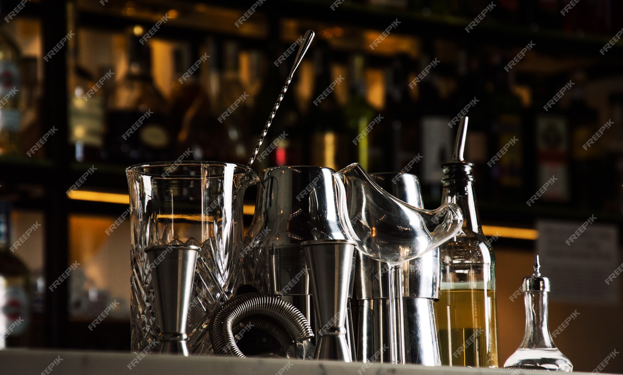 Ensemble D'accessoires De Bar Pour Faire Des Cocktails, Situé Sur Le Bar,  Derrière Se Trouve Une étagère Avec Des Liqueurs Et De L'alcool Fort.  Technique Mixte