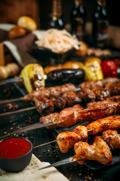 Ensemble appétissant de brochettes de brochettes avec sauce rouge et oignon mariné sur un tableau noir