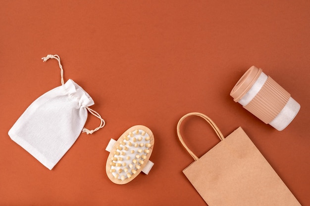 Ensemble d'articles réutilisables pour un style de vie écologique. Sac en coton et papier écologique, tasse à café, brosse à cheveux sur surface brune.