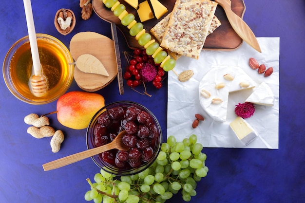 Ensemble ou assortiment de fromages libre Différentes sortes de fromages aux noix baies fruits confiture de cerises et miel sur fond bleu