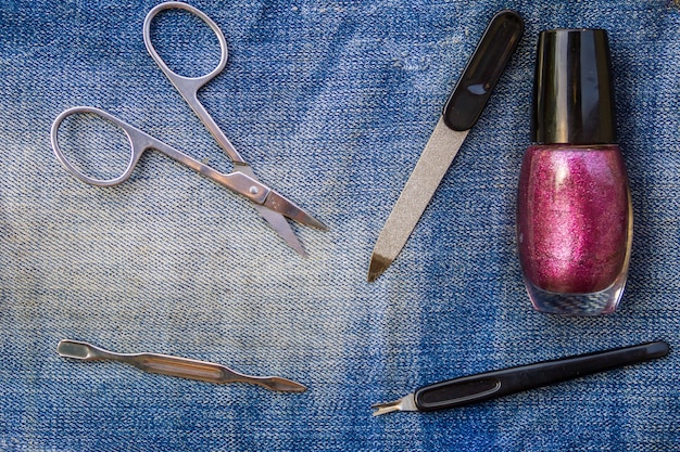 Ensemble de base d'outils de manucure sur fond de jeans. Ciseaux à ongles et à cuticules, coupe-cuticules, lime à ongles, vernis à ongles
