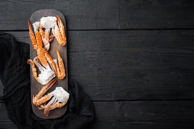 Ensemble bouilli de chair de crabe blanc brun mélangé, sur fond de table en bois noir, vue de dessus à plat, avec fond et espace pour le texte