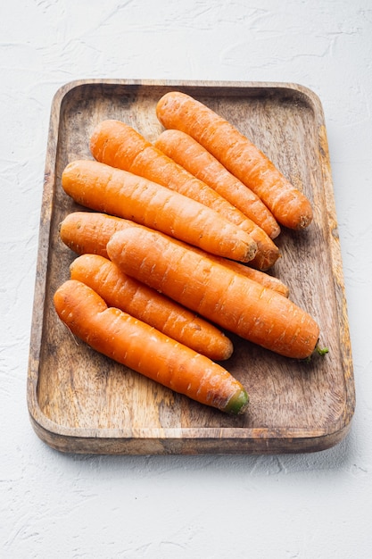 Ensemble de bouquets de carottes fraîches et sucrées, sur plateau en bois, sur fond blanc