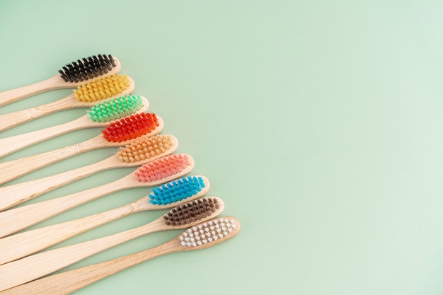 Un ensemble de brosses à dents antibactériennes écologiques en bois de bambou sur fond vert clair. Tendances de la protection de l'environnement.