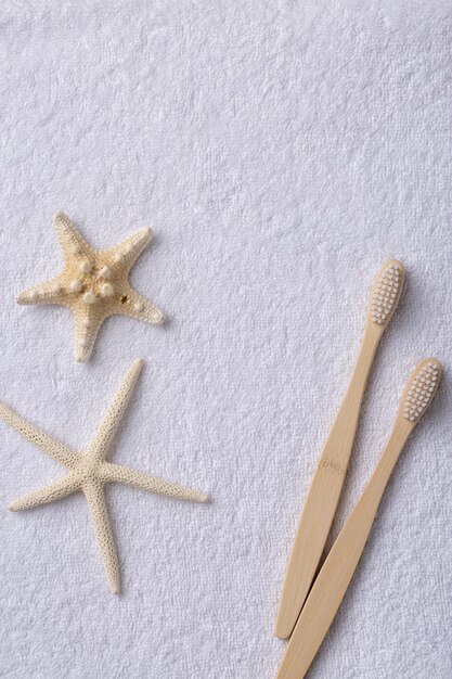 Un ensemble de brosses à dents en bois de bambou écologiques avec des étoiles de mer sur une serviette blanche