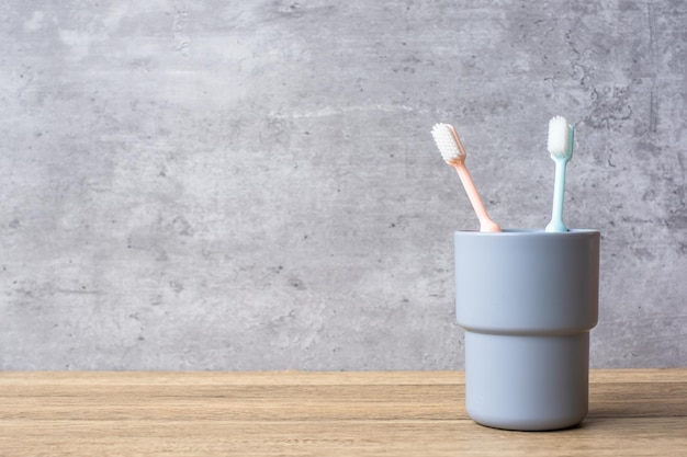 Ensemble de brosses à dents dans une tasse sur fond de mur dans la salle de bain Journée mondiale de la santé bucco-dentaire et concept de journée dentaire gratuite