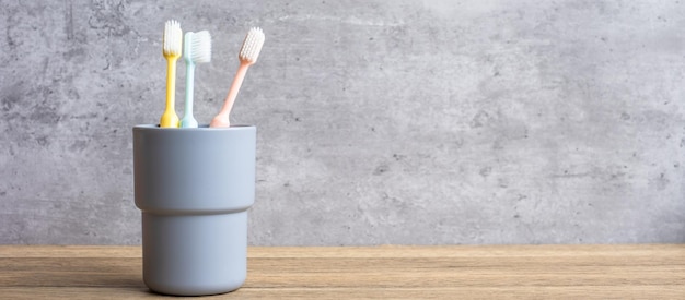 Ensemble de brosses à dents dans une tasse sur fond de mur dans la salle de bain Journée mondiale de la santé bucco-dentaire et concept de journée dentaire gratuite