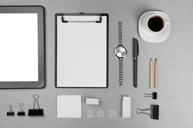 Ensemble de bureau avec des feuilles blanches de tasse de papier de montre à café et de papeterie sur fond gris