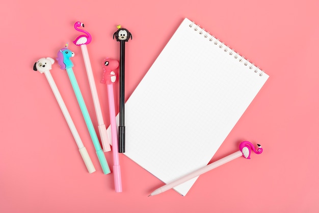 Ensemble de cahiers de notes et de stylos sur fond rose