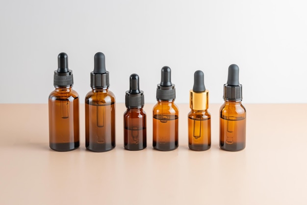 Ensemble de célèbres flacons compte-gouttes aux huiles essentielles de sérum de beauté pour le visage avec des vitamines et des extraits de peptides de collagène sur fond beige