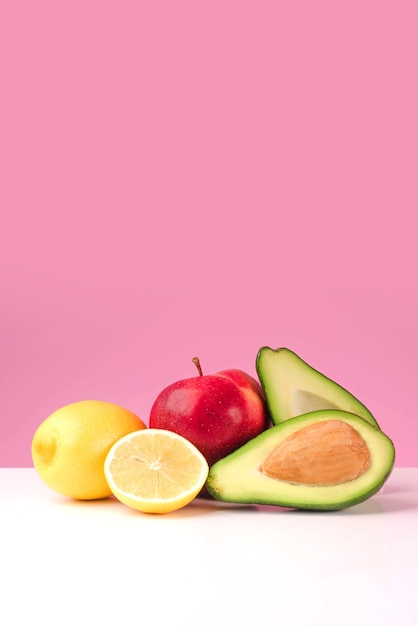 Ensemble de citron juteux frais, pomme, avocat isolé sur fond rose