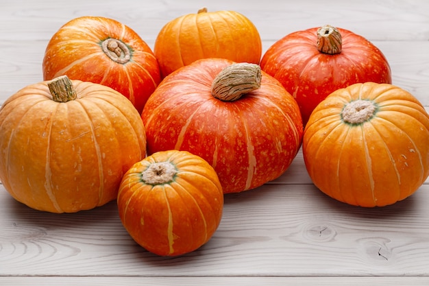 Ensemble de citrouilles rondes mûres jaunes et orange sur une surface en bois clair.