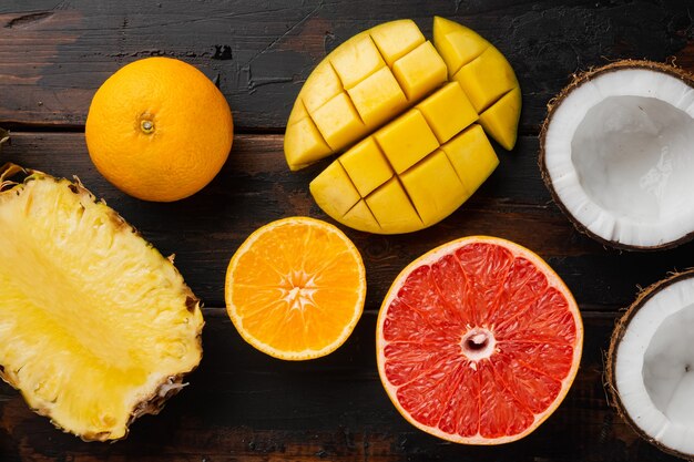 Ensemble de composition tropicale de fruits frais, sur un vieux fond de table en bois foncé, vue de dessus à plat